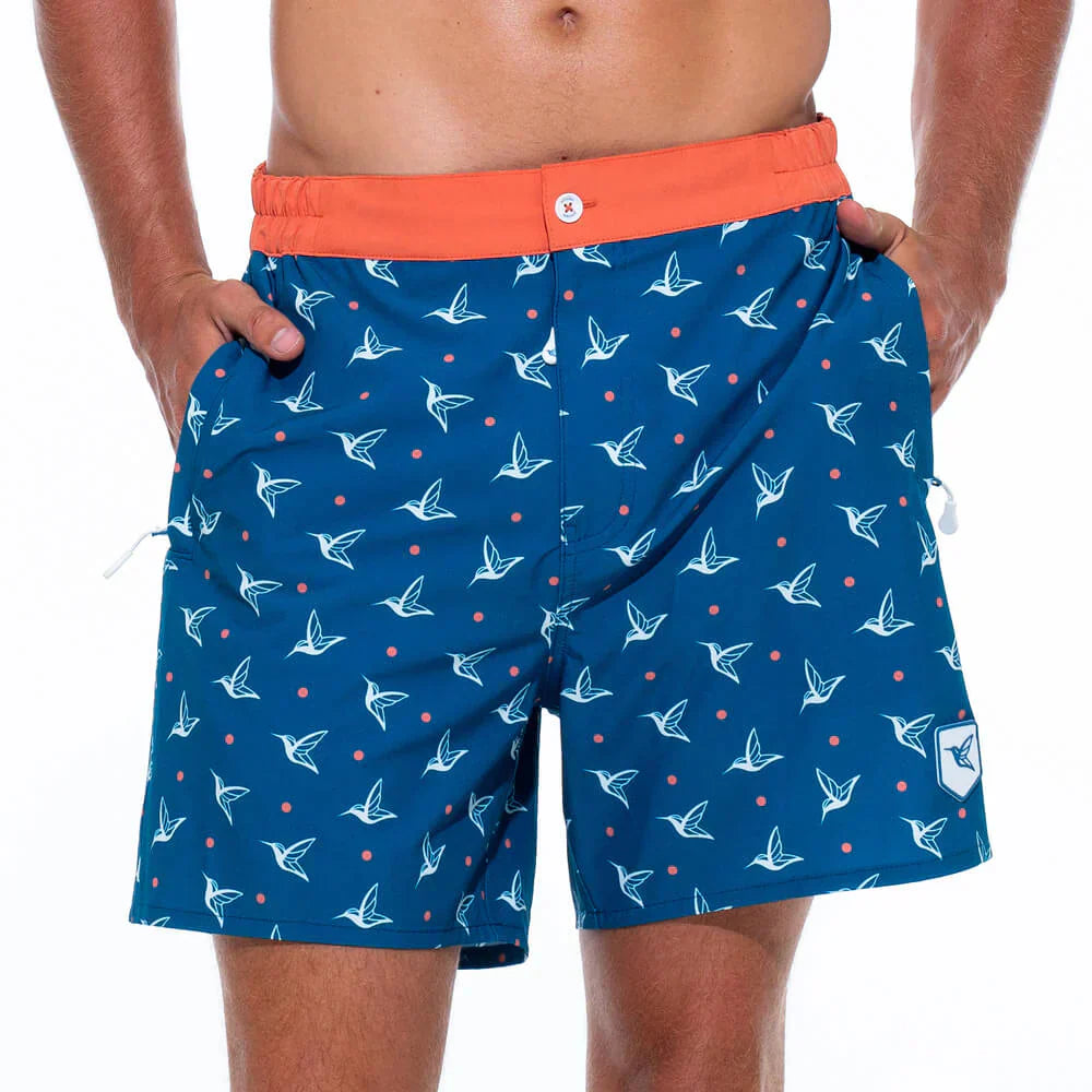 This image features a pair of Live Kolibri men's luxury swim trunks in the "Kolibri Monogram" pattern, specifically the Deep Ocean colorway. 